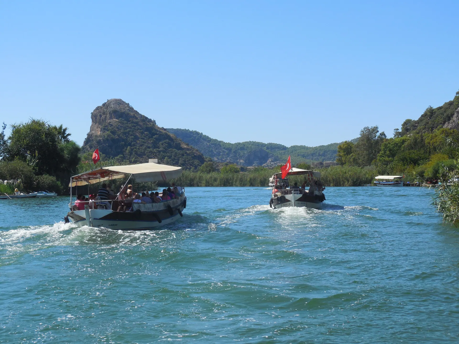 Traditional river boats on the turquoise Dalyan River below wooded cliffs